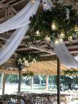 a pavilion with tables and the ceiling decorated with white cloth and green garland